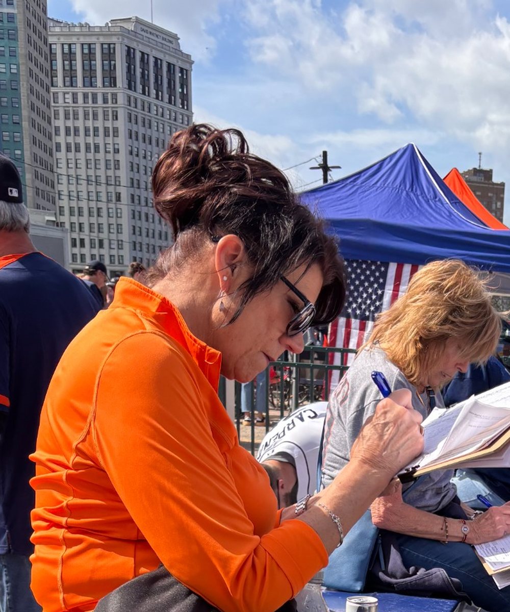 A Victory Field Operations team member completing petition paperwork during a field operation in a busy public setting.